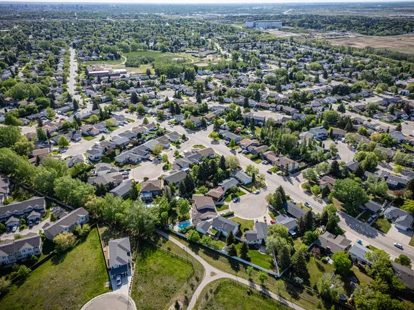 Evleri ve havuzu olan bir yerleşim yeri. Evlerin çoğu beyaz ve caddeye park etmiş birkaç araba var.