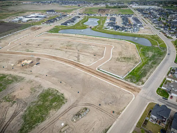 Ortasında büyük boş bir arazinin olduğu bir yerleşim alanı manzarası. Her yer evler ve göllerle çevrili.
