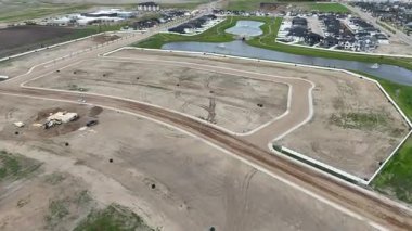 Bir sürü kir ve arka planda birkaç bina olan bir şantiye manzarası. İnşaat alanı bir su kütlesinin yanında.