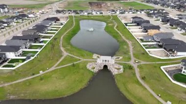 Ortasında büyük bir gölet olan yerleşim yeri manzarası. Gölet evler ve çitlerle çevrili.