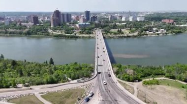 Nehir üzerinde köprüsü olan bir şehir. Köprü arabalar ve kamyonlarla dolu. Şehir yaşam ve hareketlilikle dolu.