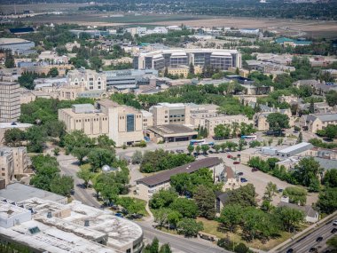 Şehir manzarası yukarıdan, ortada büyük bir hastane var. Hastane ağaçlar ve binalarla çevrili.