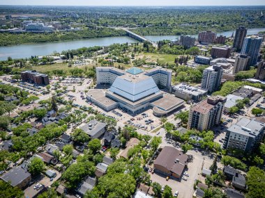 Şehir manzaralı, merkezinde büyük bir bina var. Bina ağaçlar ve arabalarla çevrili.