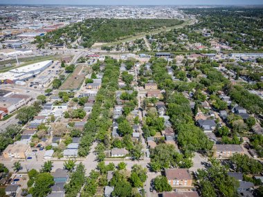 Şehir manzarası yukarıdan evler ve ağaçlarla çevrili. Evler küçük ve ağaçlar yeşil.