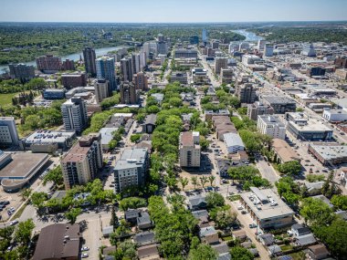 Şehir manzarası yukarıdan birçok bina ve ağaçla dolu. Şehir arabalarla ve etrafta dolaşan insanlarla oldukça meşgul görünüyor.