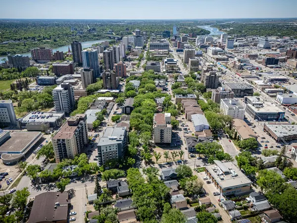 Şehir manzarası yukarıdan birçok bina ve ağaçla dolu. Şehir arabalarla ve etrafta dolaşan insanlarla oldukça meşgul görünüyor.