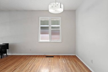 Penceresi ve lambası olan büyük bir oda. Oda boş ve minimalist bir görünüşü var.