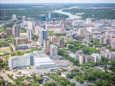 Şehir manzarası yukarıdan ortada büyük beyaz bir bina. Şehir yüksek binalarla dolu ve içinden bir nehir akıyor.