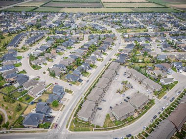 Evleri ve caddeleri olan bir yerleşim yeri. Evlerin çoğu beyaz ve caddeye park edilmiş arabalar var.