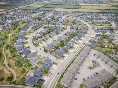 Evleri ve caddeleri olan bir yerleşim yeri. Evlerin çoğu beyaz ve caddeye park edilmiş arabalar var.