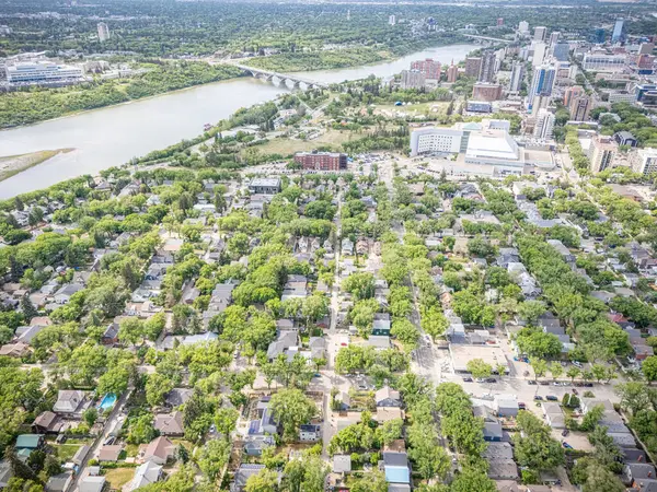 Şehir manzarası yukarıdan, içinden bir nehir akıyor. Evlerin çoğu yeşil ve caddede birkaç araba var.