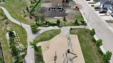 Çocuk parkı ve patikası olan bir park. Oyun parkında bir erkek ve bir kadının heykeli var.