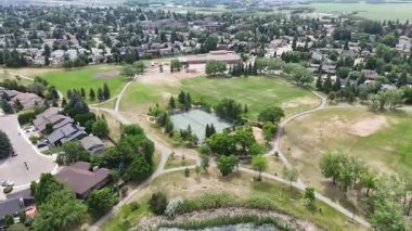 Park with a tennis court and a playground. The park is surrounded by houses. The houses are mostly white and brown