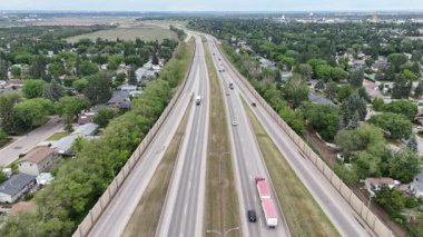 Otoyol, arkasında çit olan uzun ve düz bir yoldur. Yolda giden birçok araba var, bazıları kırmızı ışıkta durduruluyor. Gökyüzü bulutlu.