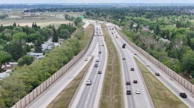 Üzerinde arabalar olan bir otoyol ve arka planda uzun bir bina. Sahne meşgul ve hareketli.