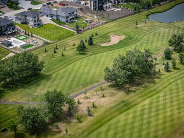 Arka planda evi olan bir golf sahası. Golf sahası iyi korunuyor ve yeşil çimenli bir alanı var.