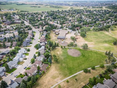 Ortasında park olan bir yerleşim yeri manzarası. Park boş ve evler yayılmış.