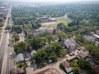 Bir sürü ağaç ve ev olan şehir manzarası. Evler çoğunlukla küçük ve cadde arabalar ve kamyonlarla dolu.