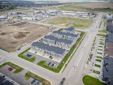 Bir sürü evi ve birkaç arabası olan bir yerleşim yeri. Evler dizildi ve caddeye park etmiş birkaç araba var.
