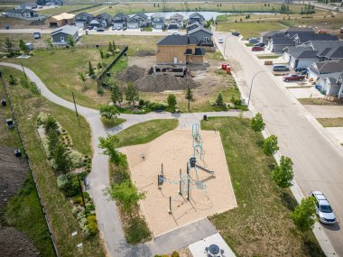 Bir oyun parkı ve birkaç ağacı olan bir park yeri. Park yerleşim bölgesinde yer almaktadır. Cadde boyunca park edilmiş birkaç araba var.