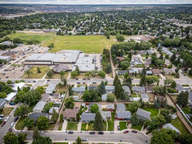 Bir okul ve birkaç evi olan bir şehir manzarası. Evler çoğunlukla beyaz ve arabalar çoğunlukla kırmızı.