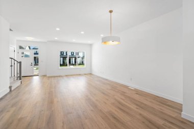 Beyaz kapısı ve penceresi olan büyük, boş bir oturma odası. Oda çok temiz ve modern bir havası var.