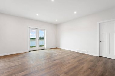 Göl manzaralı büyük, boş bir oda. Oda çok temiz ve pencerelerden gelen bir sürü doğal ışık var.