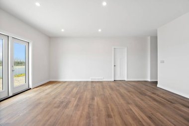 Büyük, beyaz kapısı ve penceresi olan boş bir oda. Oda boş ve boş. Mobilya ya da dekorasyon yok. Beyaz duvarlar ve ahşap zeminler odayı temiz ve minimalist gösteriyor.