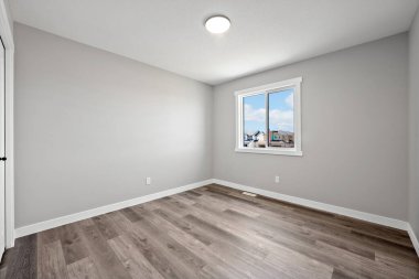 Büyük, penceresi ve aydınlatma armatürü olan boş bir oda. Oda çok temiz ve çok basit bir tasarımı var.