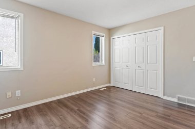 Büyük, beyaz kapısı ve penceresi olan boş bir oda. Oda çıplak ve dağınık. Mobilya ya da dekorasyon yok. Beyaz kapı ve pencere odaya temiz ve minimalist bir hava veriyor.