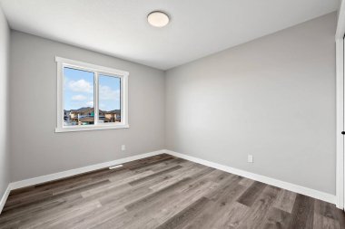 Büyük, penceresi ve aydınlatma armatürü olan boş bir oda. Oda çok temiz ve çok basit bir tasarımı var.