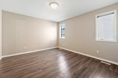 Ahşap zemini ve beyaz tavanı olan büyük, boş bir oda. Oda çıplak ve dağınık. Mobilya ya da dekorasyon yok. Alan açık ve havadar ama aynı zamanda soğuk ve verimsiz.