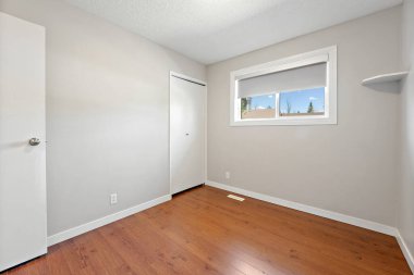 Ahşap zemini ve beyaz duvarı olan küçük, boş bir oda. Oda çıplak ve dağınık. Mobilya ya da dekorasyon yok. Pencereden gelen ışık sıcak ve davetkar bir atmosfer yaratıyor.