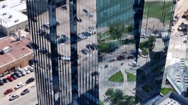 Bir sürü penceresi ve camında arabaların yansıması olan büyük bir bina. Bina içinde birçok arabanın park edildiği bir otoparkla çevrili.