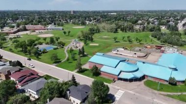 Bir sürü penceresi ve camında arabaların yansıması olan büyük bir bina. Bina içinde birçok arabanın park edildiği bir otoparkla çevrili.