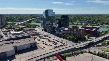 Bir sürü penceresi ve camında arabaların yansıması olan büyük bir bina. Bina içinde birçok arabanın park edildiği bir otoparkla çevrili.