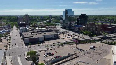 Bir sürü penceresi ve camında arabaların yansıması olan büyük bir bina. Bina içinde birçok arabanın park edildiği bir otoparkla çevrili.