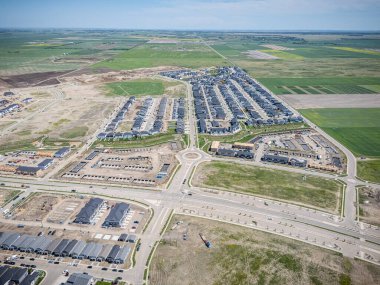 Uzaklarda birkaç evi olan büyük, boş bir arazi. Evler dağılmış durumda ve etrafta hiç insan yok.
