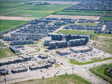 Şehir manzarası, bir sürü bina ve büyük bir otopark. Binaların çoğu beyaz ve park yerinde bir sürü araba var.