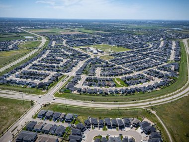Bir sürü evi ve birkaç arabası olan bir yerleşim yeri manzarası. Evlerin çoğu beyaz ve cadde ağaçlarla kaplı.