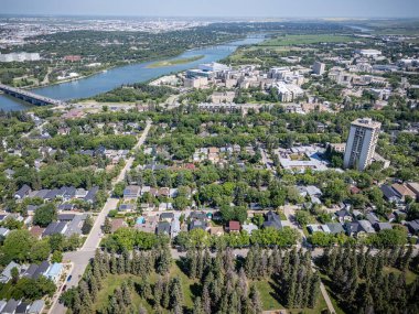 Şehir manzarası yukarıdan, içinden bir nehir akıyor. Şehir evler ve binalarla dolu ve arka planda bir köprü var.