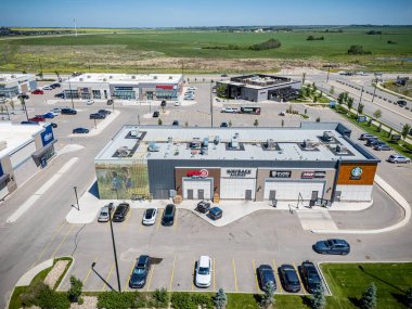 Üzerinde kırmızı işaret olan büyük bir bina. Bina otoparklarla çevrili ve içinde bir sürü araba var.