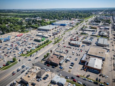 Bir sürü arabası ve binası olan bir şehir caddesi. Gökyüzü mavi ve güneş parlıyor.