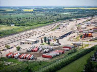 Bir sürü kırmızı beyaz kamyonu olan büyük bir tren istasyonu. Kamyonlar sıra sıra park edilmiş ve bahçe çitlerle çevrili.