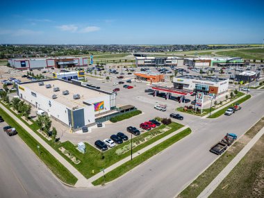 Park yerinde bir sürü araba olan büyük bir alışveriş merkezi. Alışveriş merkezi yeşil bir alanla çevrili.