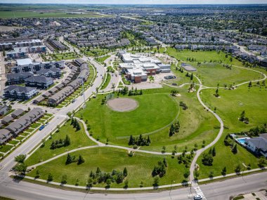 Arkasında beyaz bir ev olan büyük yeşil bir alan. Alan çitlerle çevrili ve arka planda beyaz bir ev var.