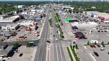 Bir sürü arabası ve binası olan bir şehir caddesi. Gökyüzü mavi ve güneş parlıyor.