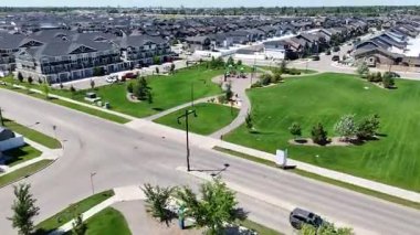 Park ve caddesi olan bir yerleşim yeri. Park evler ve ağaçlarla çevrilidir. Sokaklar arabalar ve birkaç yayayla dolu.