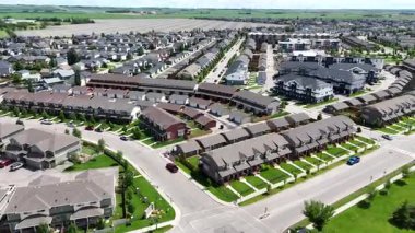 Birçok evi ve birkaç arabası olan bir yerleşim yeri. Evlerin çoğu kahverengi ve gri. Sokaklar ağaçlarla dolu ve evler birbirine yakın.