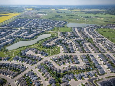 Evleri ve gölü olan bir yerleşim yeri. Evler dizildi ve caddeye park edilmiş bir sürü araba var.